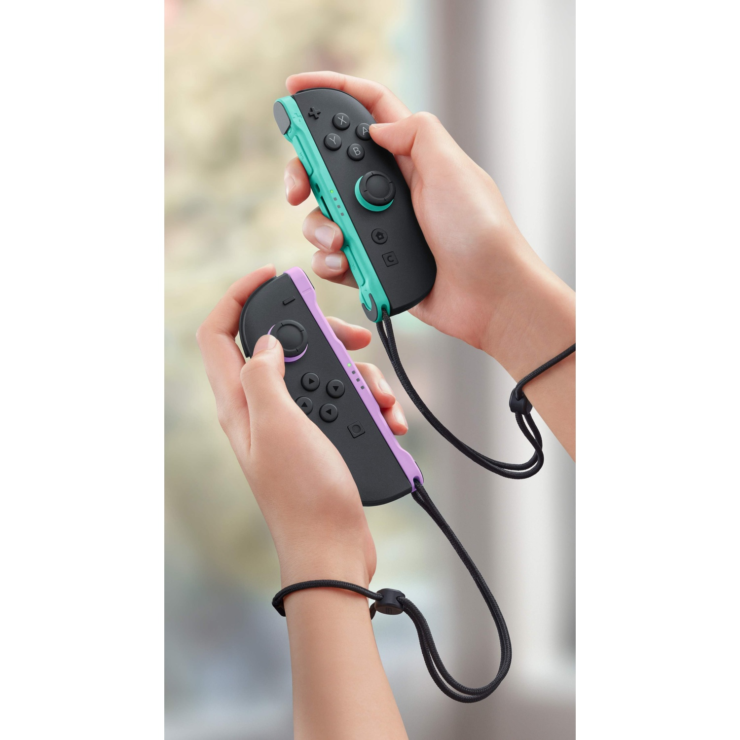 Mani che tengono due controller Joy-Con grigi con accenti verde menta e viola.