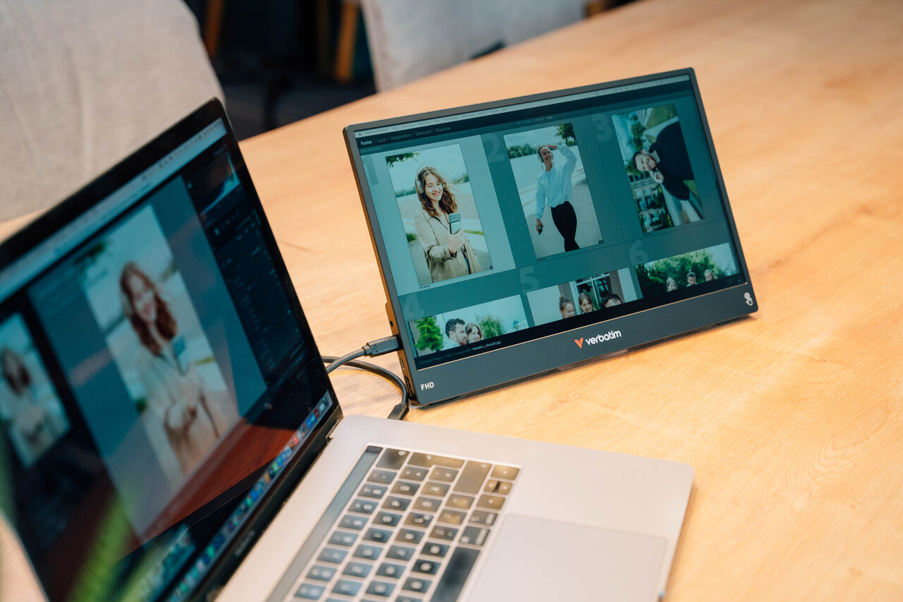 Un ordinateur portable et un moniteur externe affichent des photos sur une table en bois.