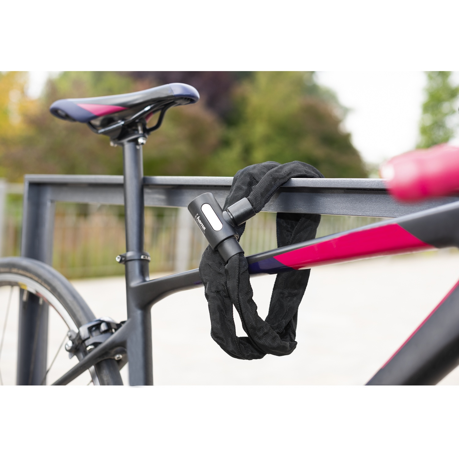 A black bicycle chain lock securing a bike frame to a railing outdoors.