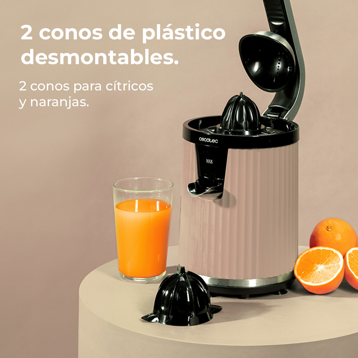 Un exprimidor rosa con un vaso de jugo, naranjas y conos desmontables.