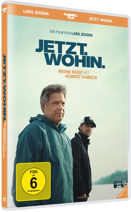 Zwei Männer stehen im Freien. Der linke Mann trägt eine blaue Jacke. Der rechte Mann trägt eine schwarze Jacke und eine Kappe.
