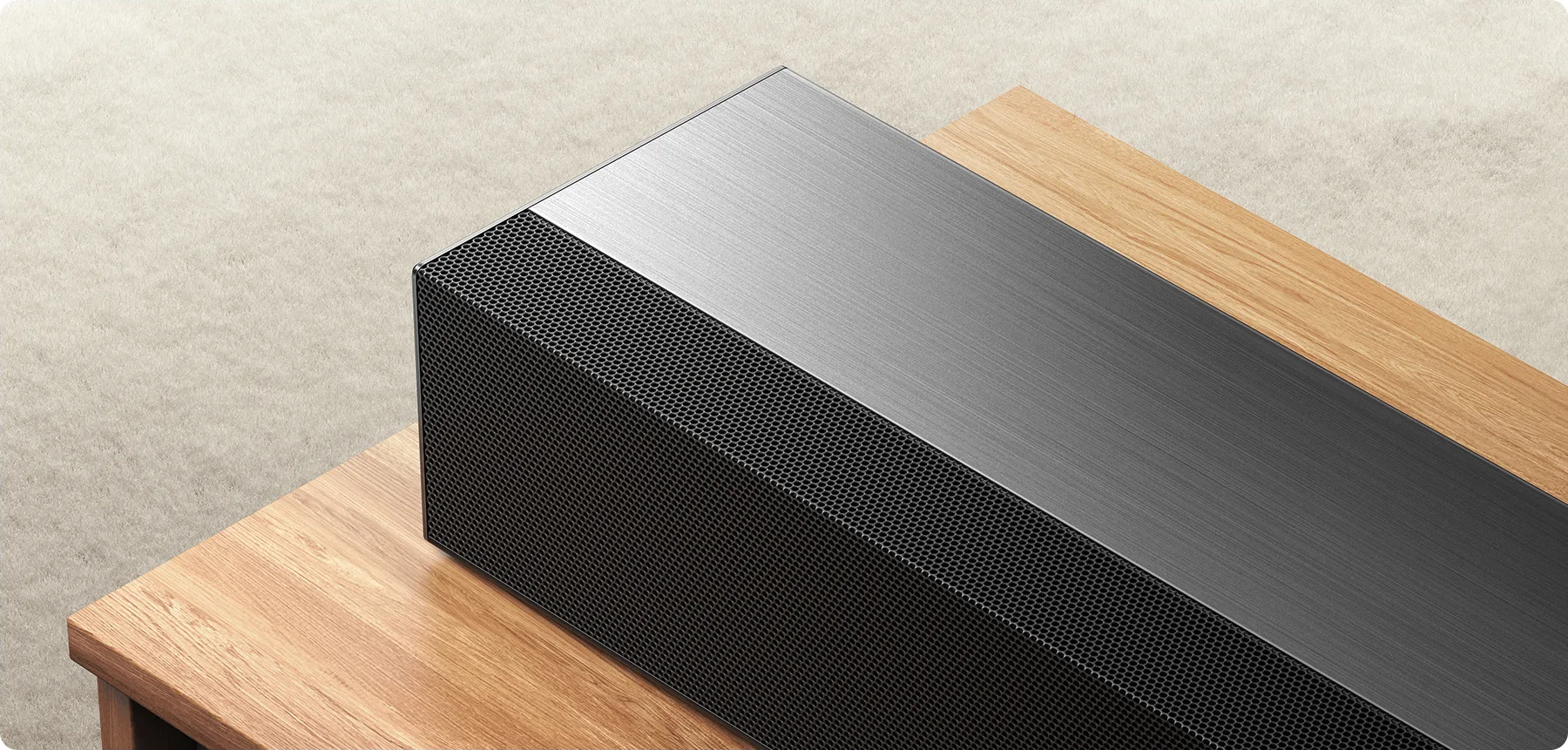 Haut-parleur noir avec grille métallique sur table en bois.