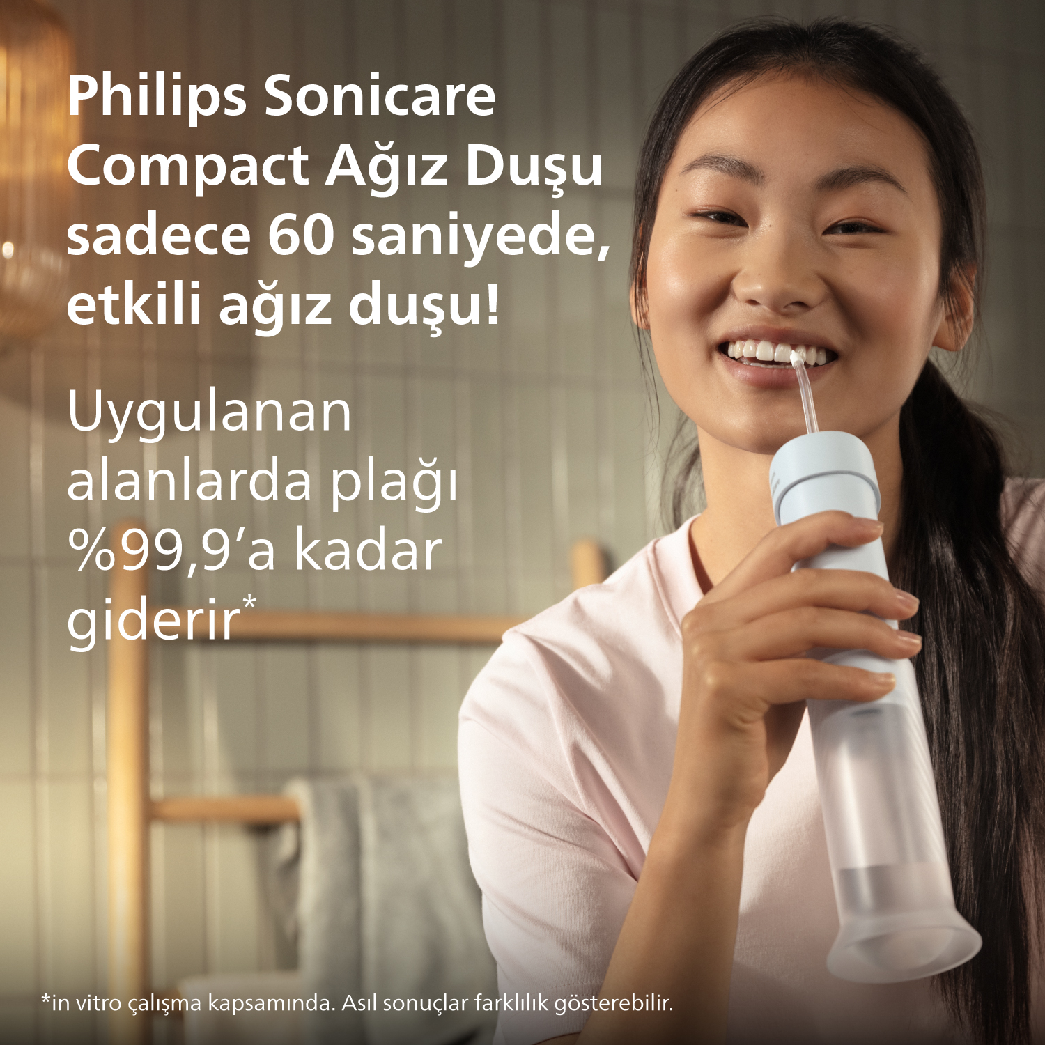 Genç kadın Philips Sonicare ağız duşu kullanıyor, gülümsüyor.