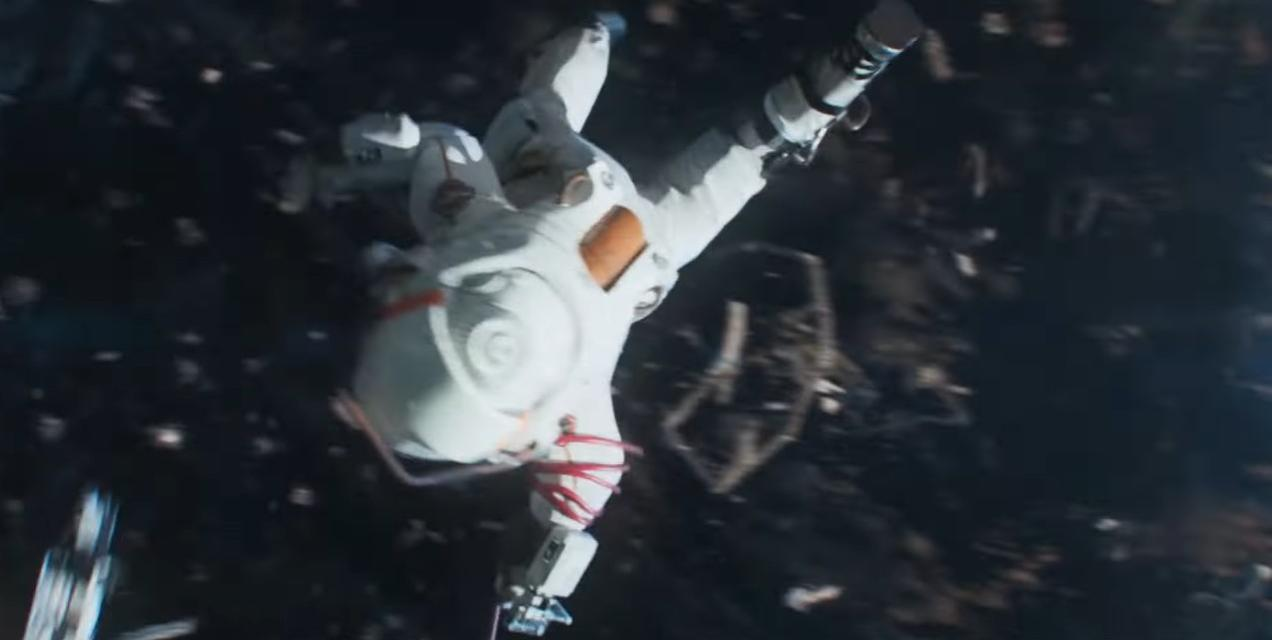 Ein Astronaut in einem weißen Raumanzug treibt im Weltraum, umgeben von Trümmern.