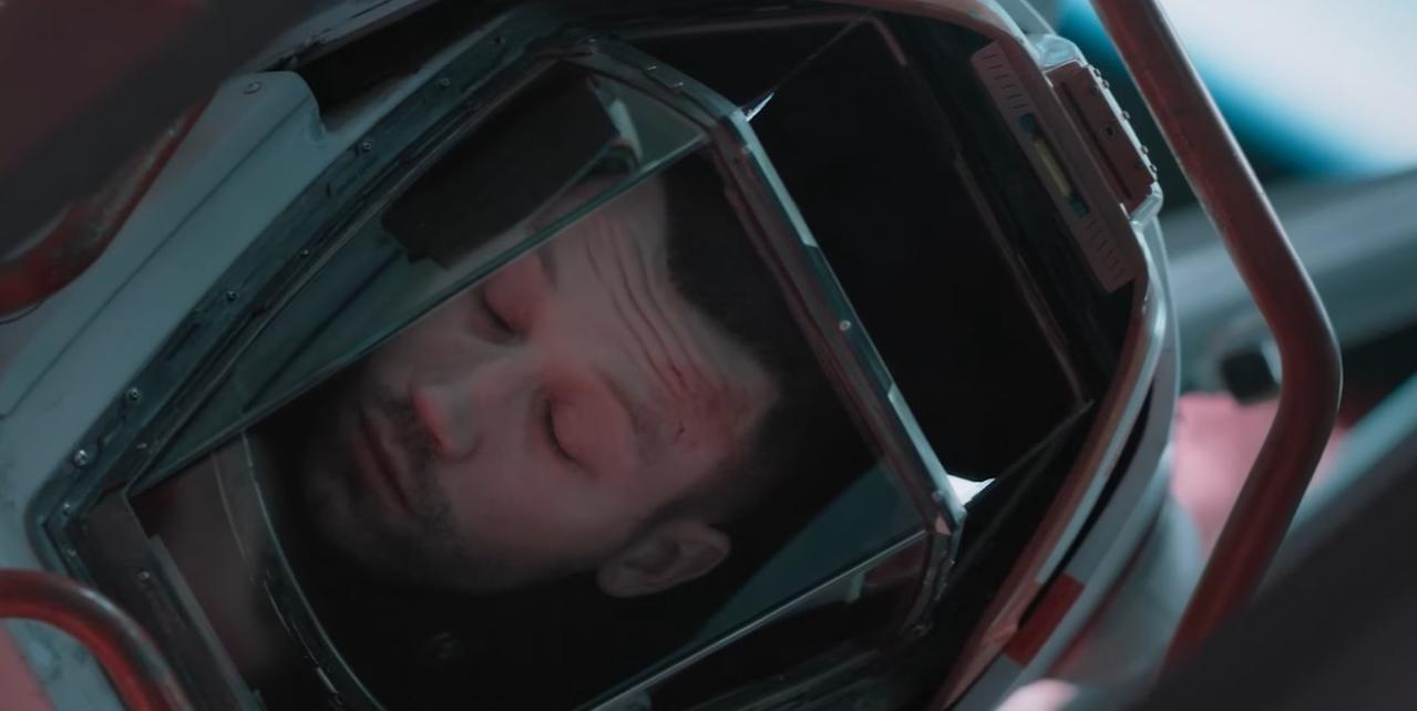 Ein Mann in einem Helm mit geschlossenen Augen und Schrammen auf der Stirn.