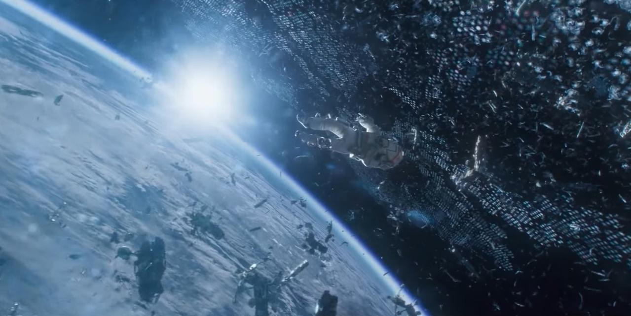Ein Raumschiff fliegt durch Trümmer vor einer Weltraumstation über der Erde.