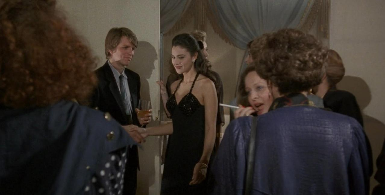 Eine Gruppe von Menschen auf einer Party. Ein Mann und eine Frau schütteln sich die Hände.