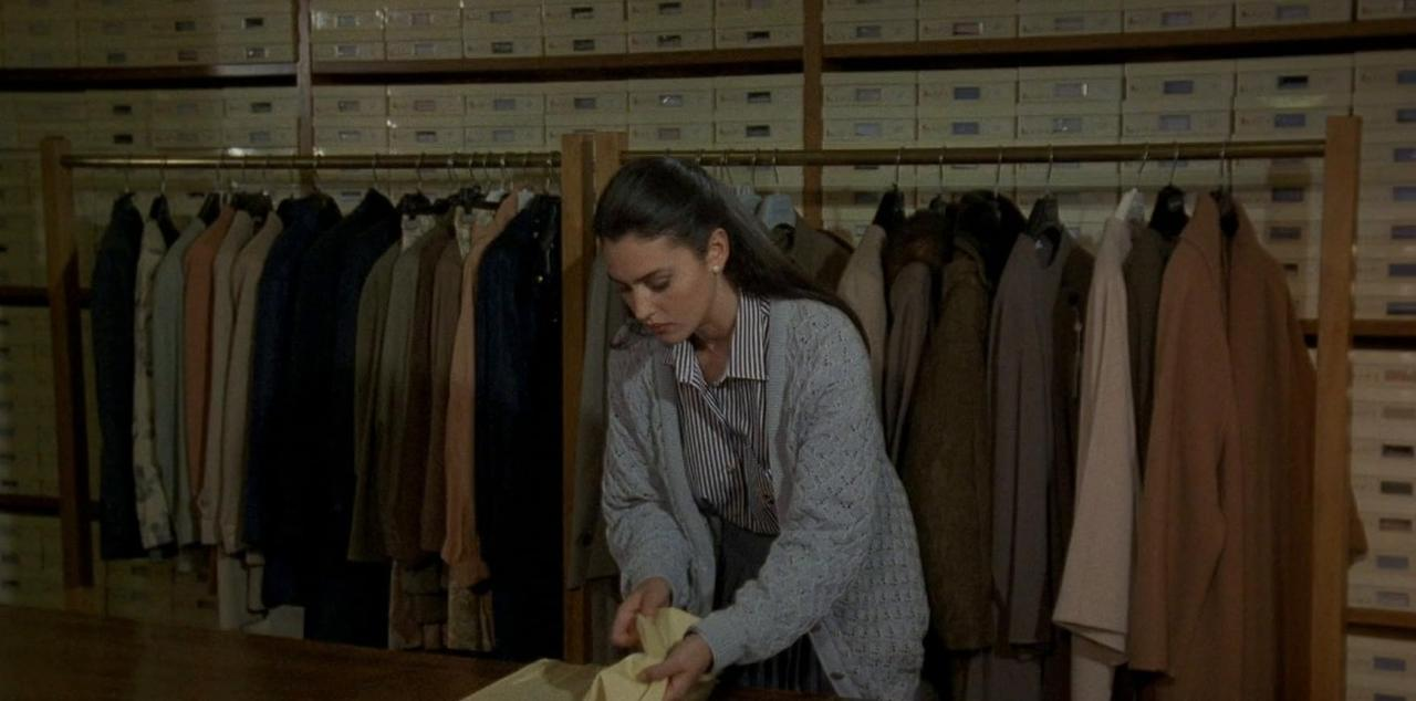Eine Frau in einem gestreiften Hemd und Strickjacke sortiert Kleidung in einem Lager.