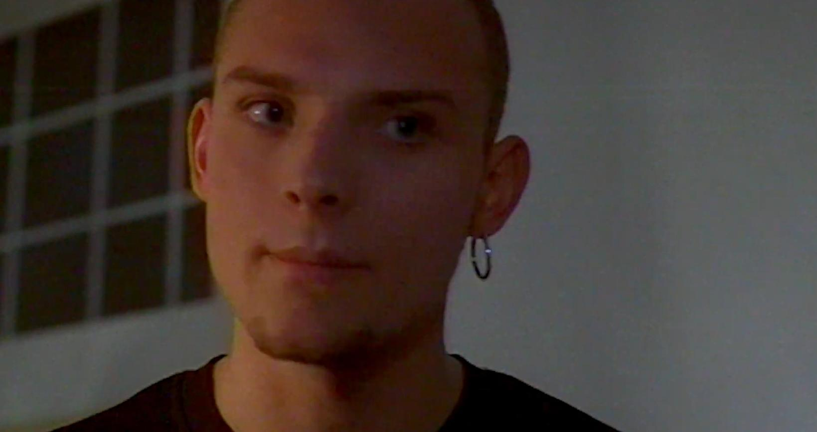 Nahaufnahme eines jungen Mannes mit Ohrring und dunklem T-Shirt.
