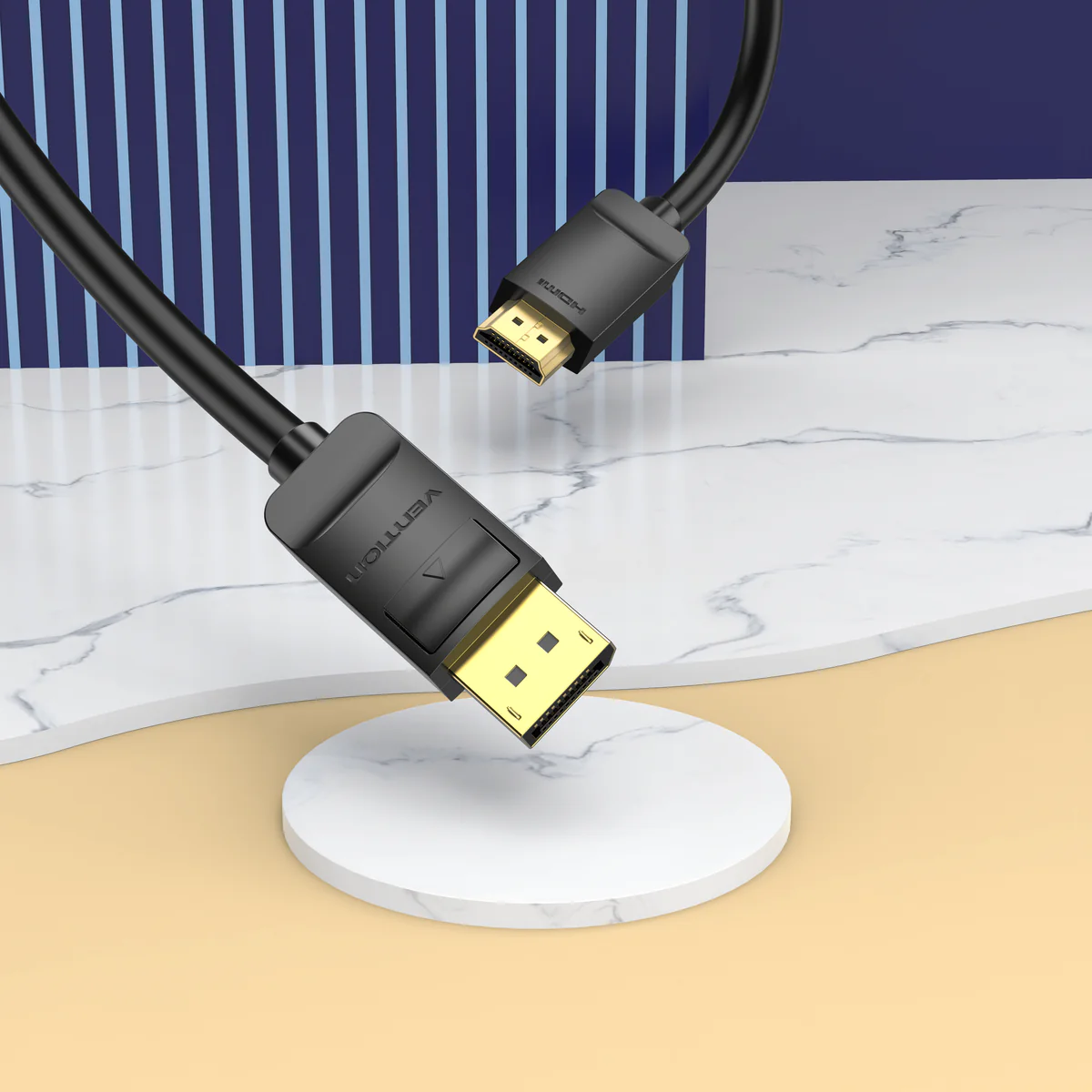 Két fekete HDMI kábel arany csatlakozókkal márvány és bézs háttéren.