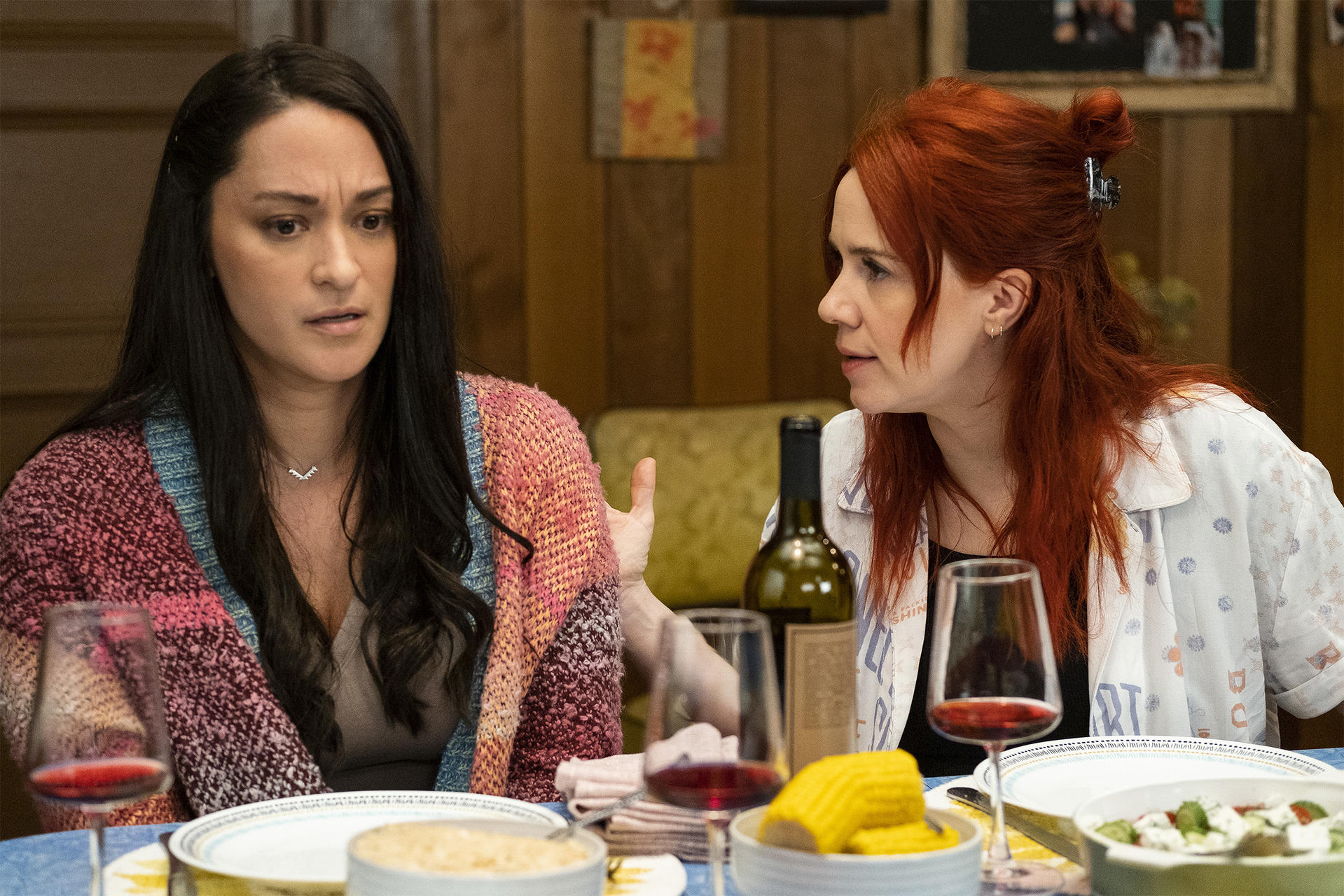 Zwei Frauen sitzen am Tisch, Wein und Essen sind auf dem Tisch.