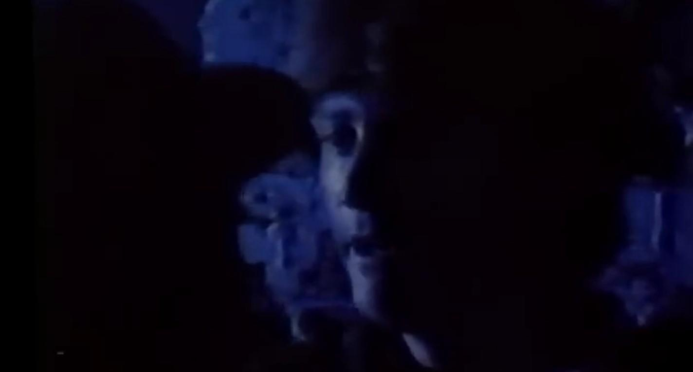 Schattiges Profil einer Person im blauen Licht, mit unscharfem Hintergrund.