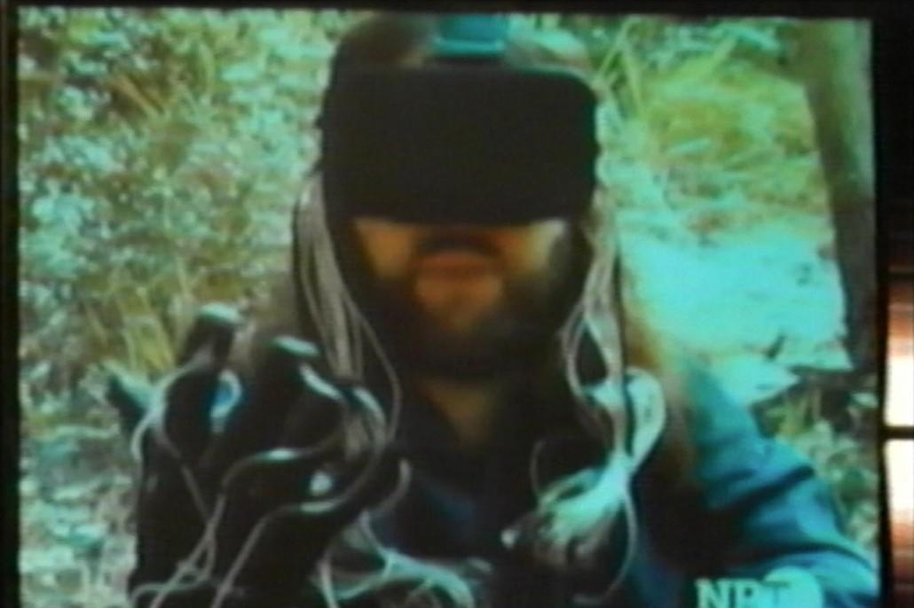 Mann mit VR-Brille und langen Haaren hält Hände mit Handschuhen nach vorne.
