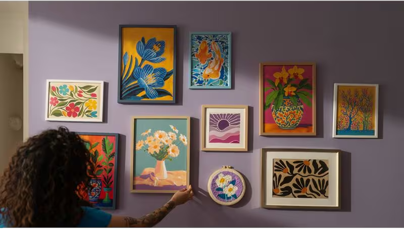 Opere d'arte colorate su una parete viola con fiori, pesci e alberi.