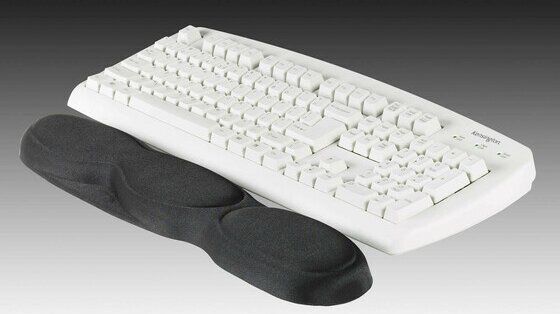 Egy fehér Kensington billentyűzet látható fekete ergonomikus csuklótámasszal előtte.
