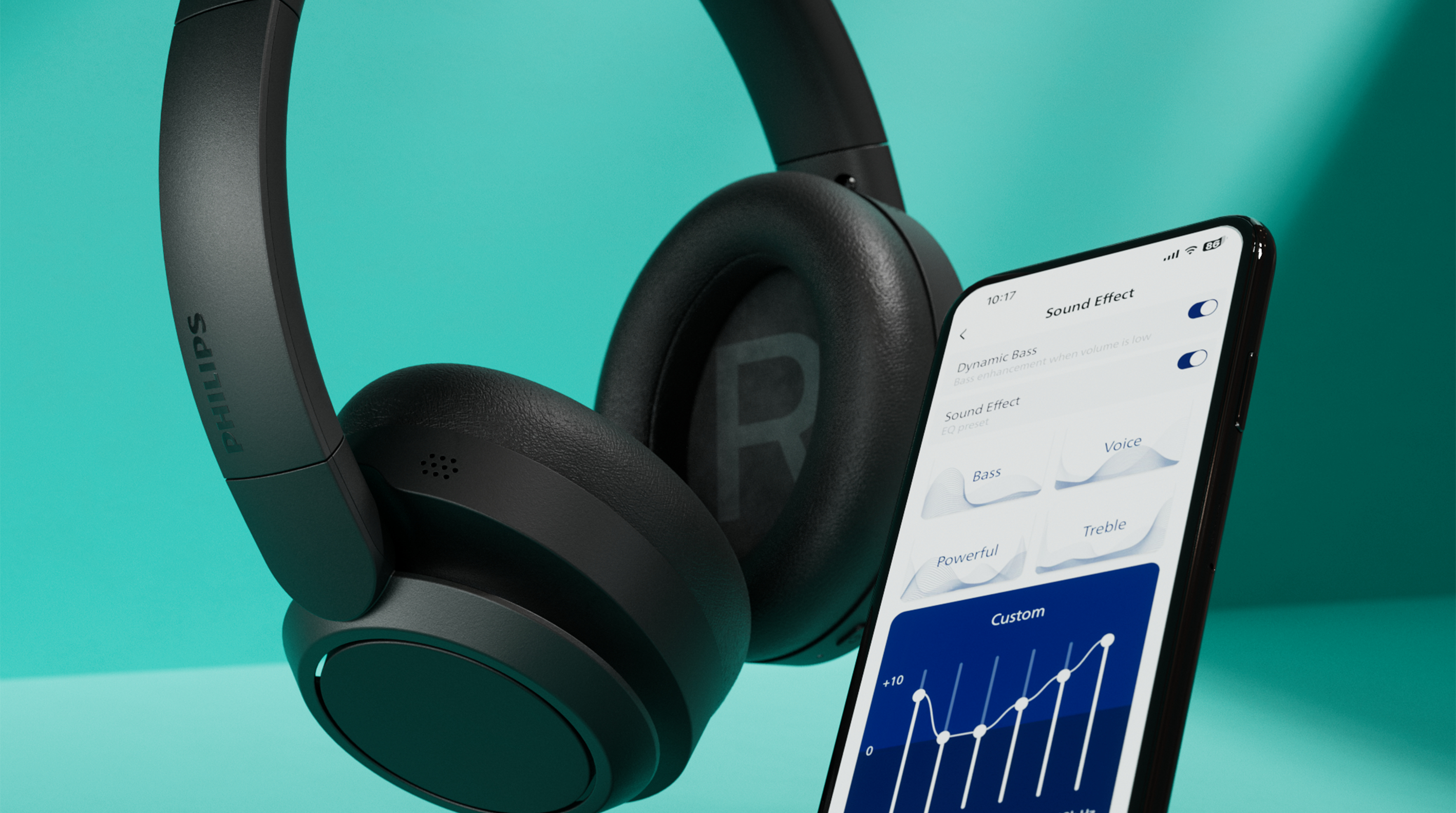 Schwarze Kopfhörer mit Philips-Logo neben einem Smartphone mit EQ-Einstellungen.