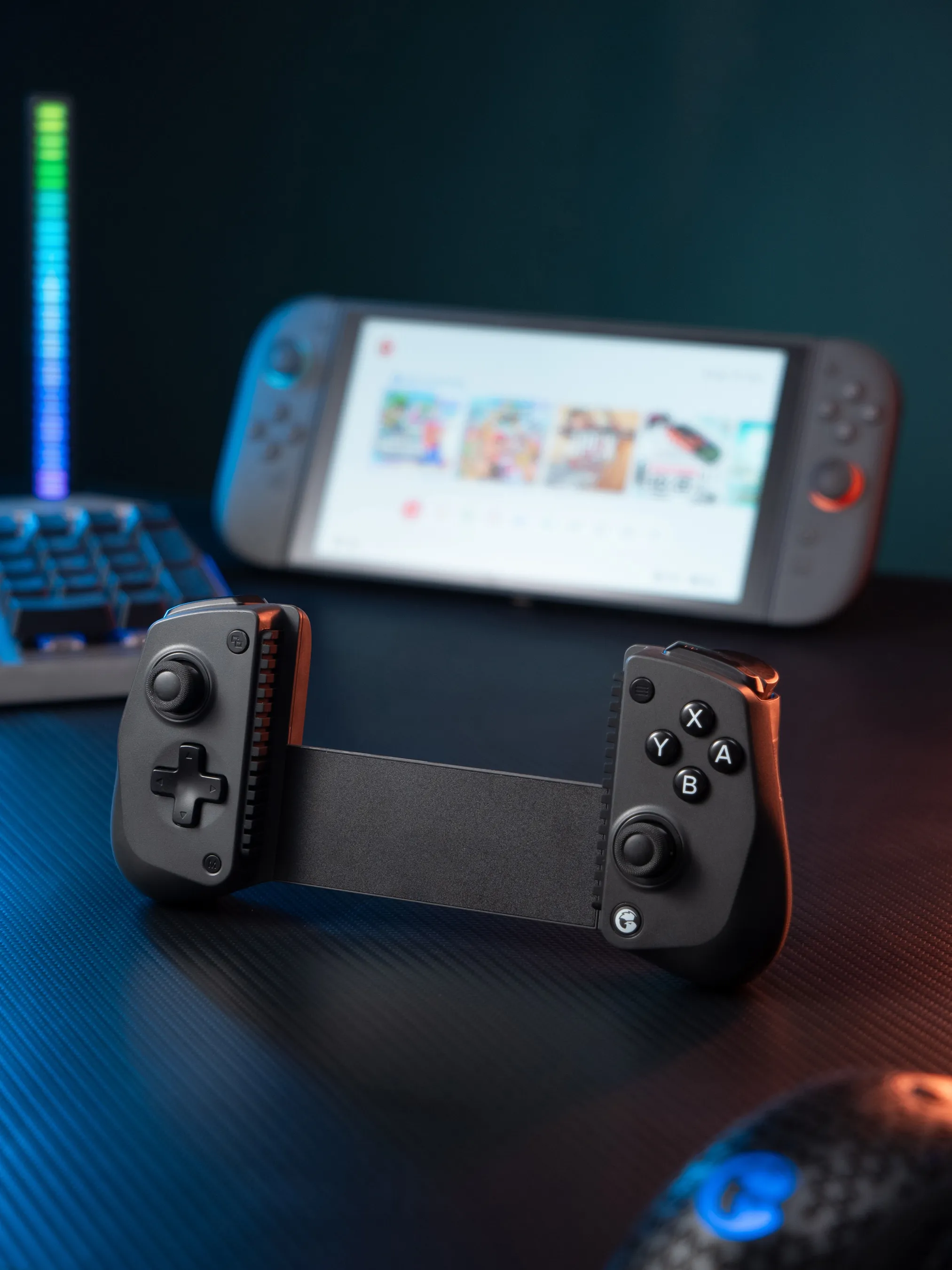 Un controller di gioco nero con pulsanti e joystick poggia su una superficie in fibra di carbonio.