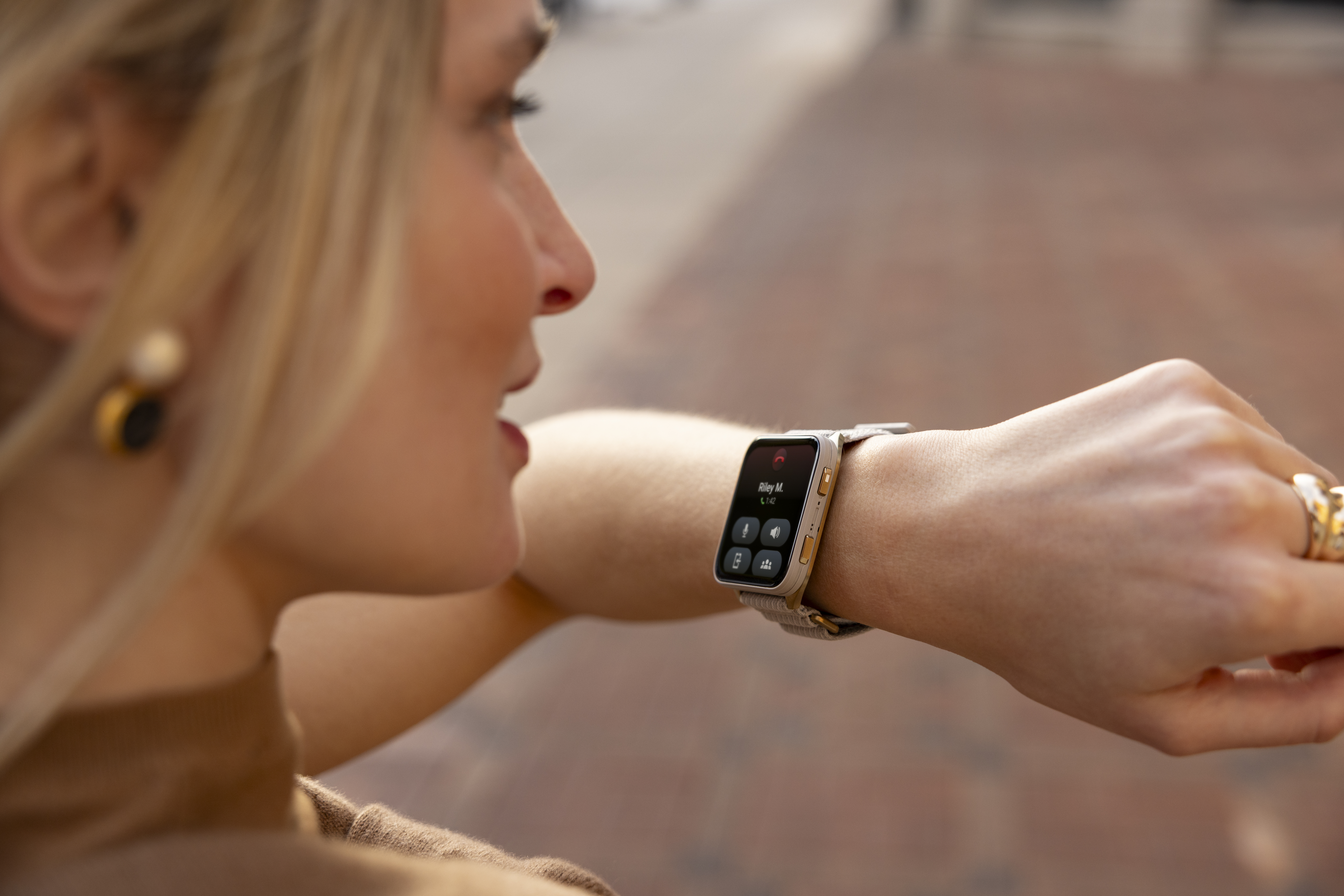 Frau mit blonden Haaren schaut auf ihr Smartwatch-Display mit Anrufdetails.