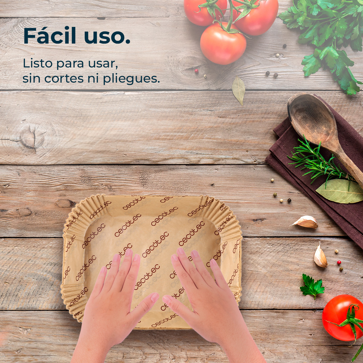 Manos sobre una bandeja de papel para hornear en mesa de madera con tomates y hierbas.