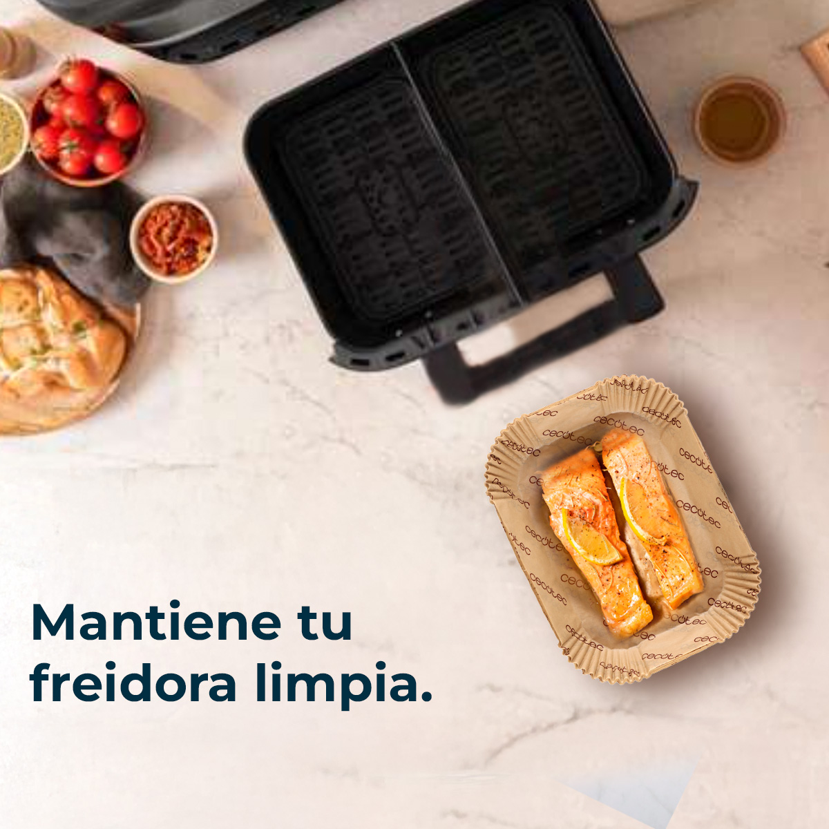Una freidora de aire negra abierta con dos compartimentos, junto a dos filetes de salmón.