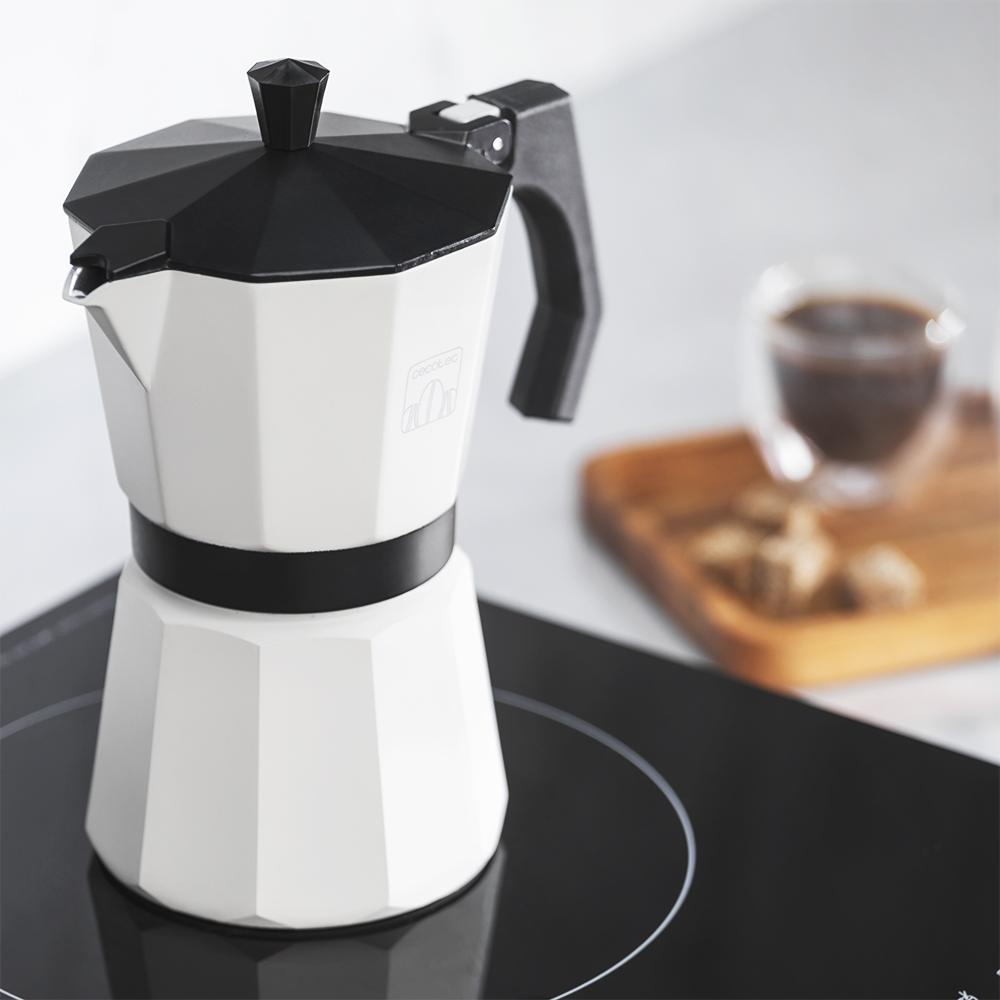 Una cafetera moka blanca con tapa negra está sobre una placa de inducción.