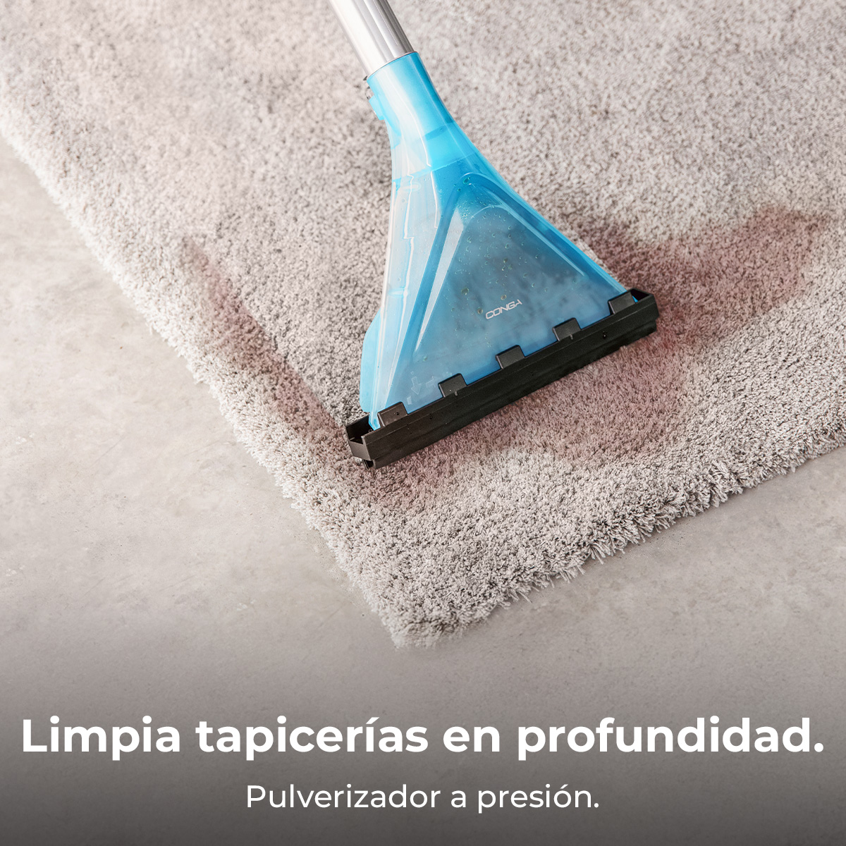 Un limpiador de alfombras azul limpia una alfombra gris sobre un suelo de hormigón.