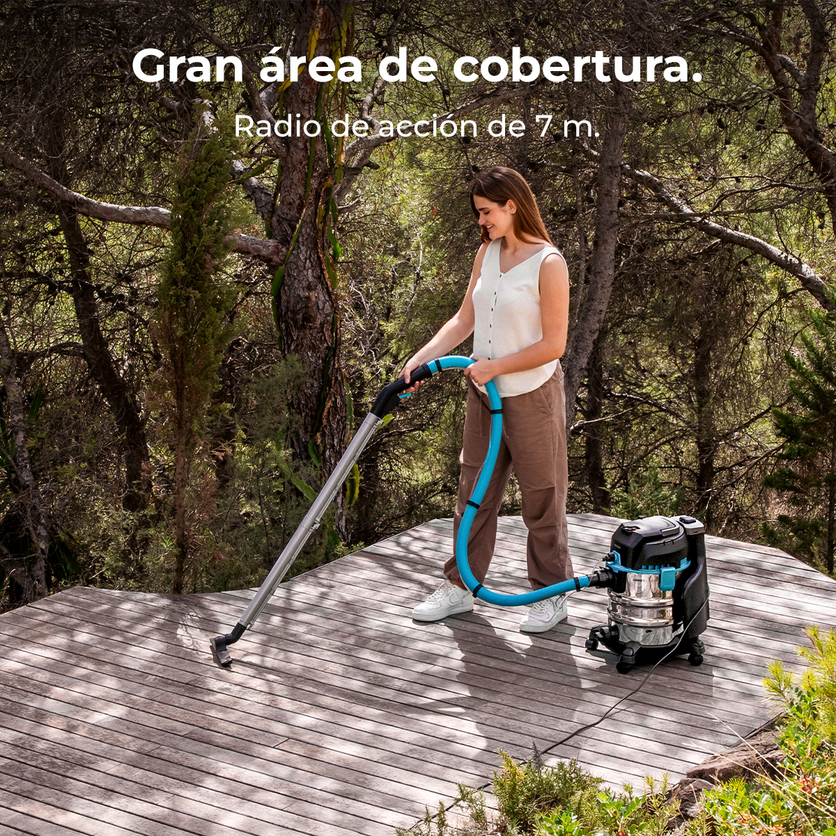 Mujer aspira terraza de madera al aire libre con aspiradora grande.
