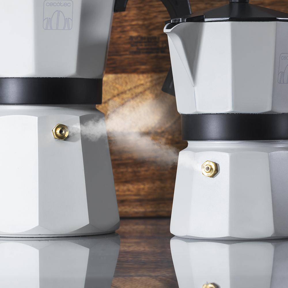 Dos cafeteras moka blancas con vapor frente a un fondo de madera.