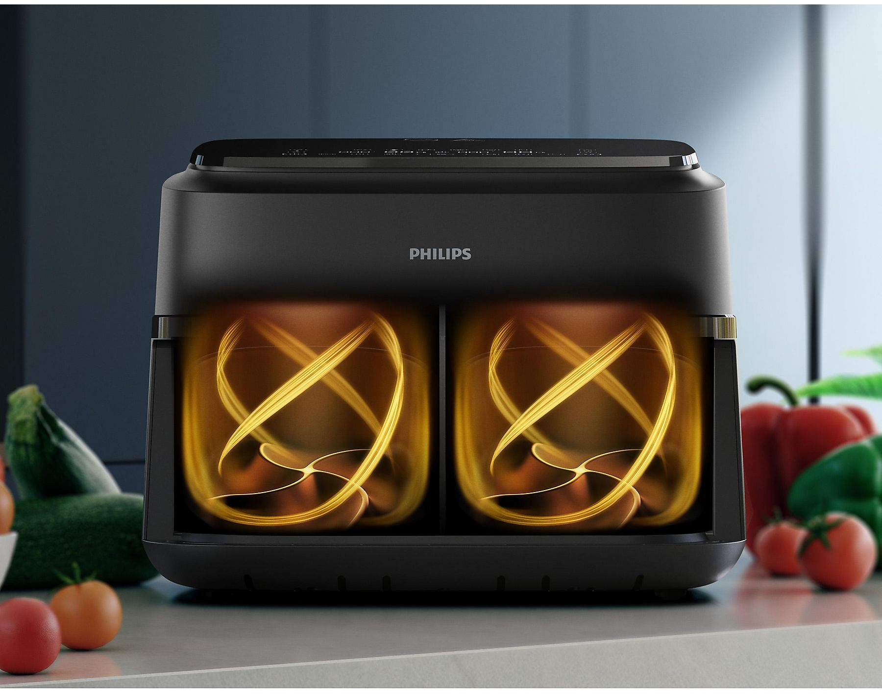 Egy fekete Philips légfritő két kosárral, narancssárga spirálokat mutatva.