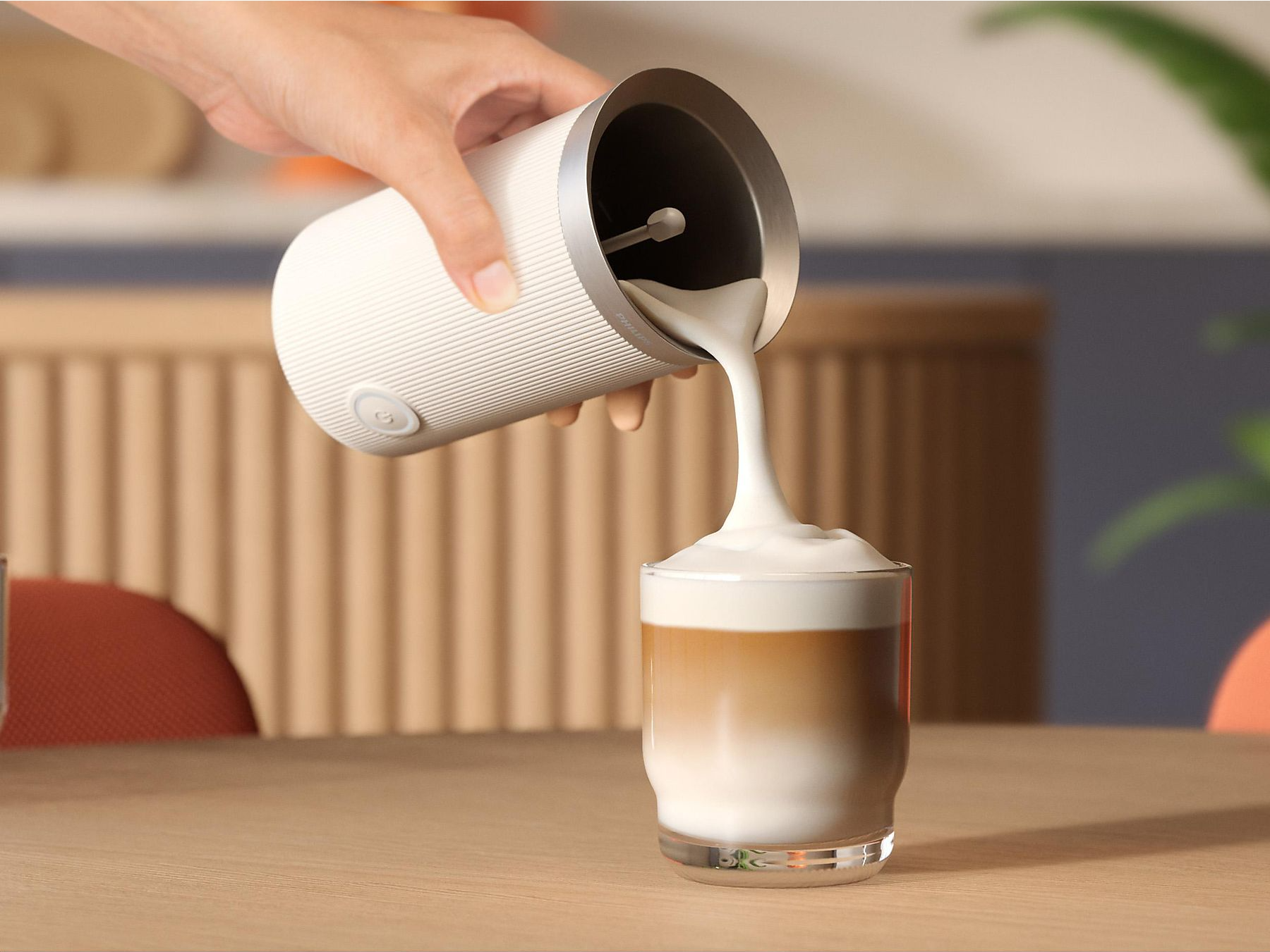 Tejet öntenek egy tartóból egy latte macchiato pohárba.