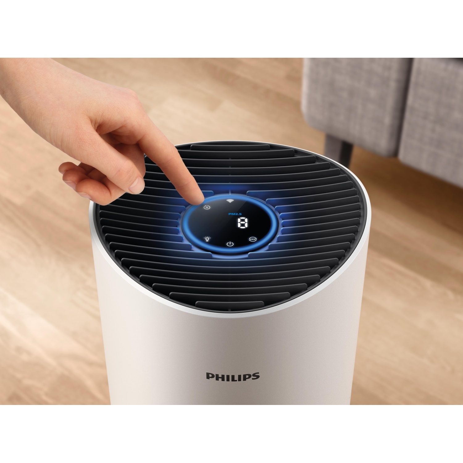 Una mano tocca il display di un purificatore d'aria Philips bianco con illuminazione blu.