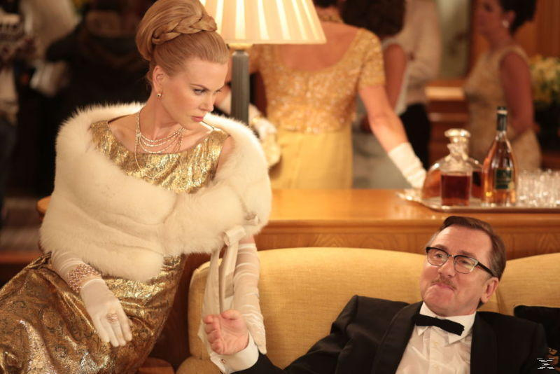 Eine Frau in einem goldenen Kleid mit Pelz und ein Mann im Smoking sitzen.