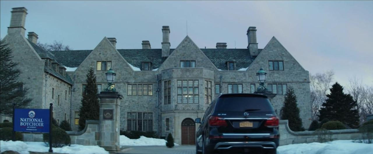 Ein großes Steinhaus mit Schild 'National Boychoir Academy' und einem schwarzen SUV.