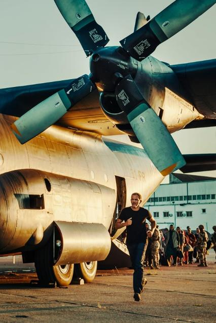 Ein Mann rennt neben einem Flugzeug. Im Hintergrund stehen Menschen.