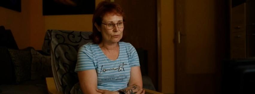 Eine Frau mit roten Haaren und Brille sitzt in einem Stuhl.