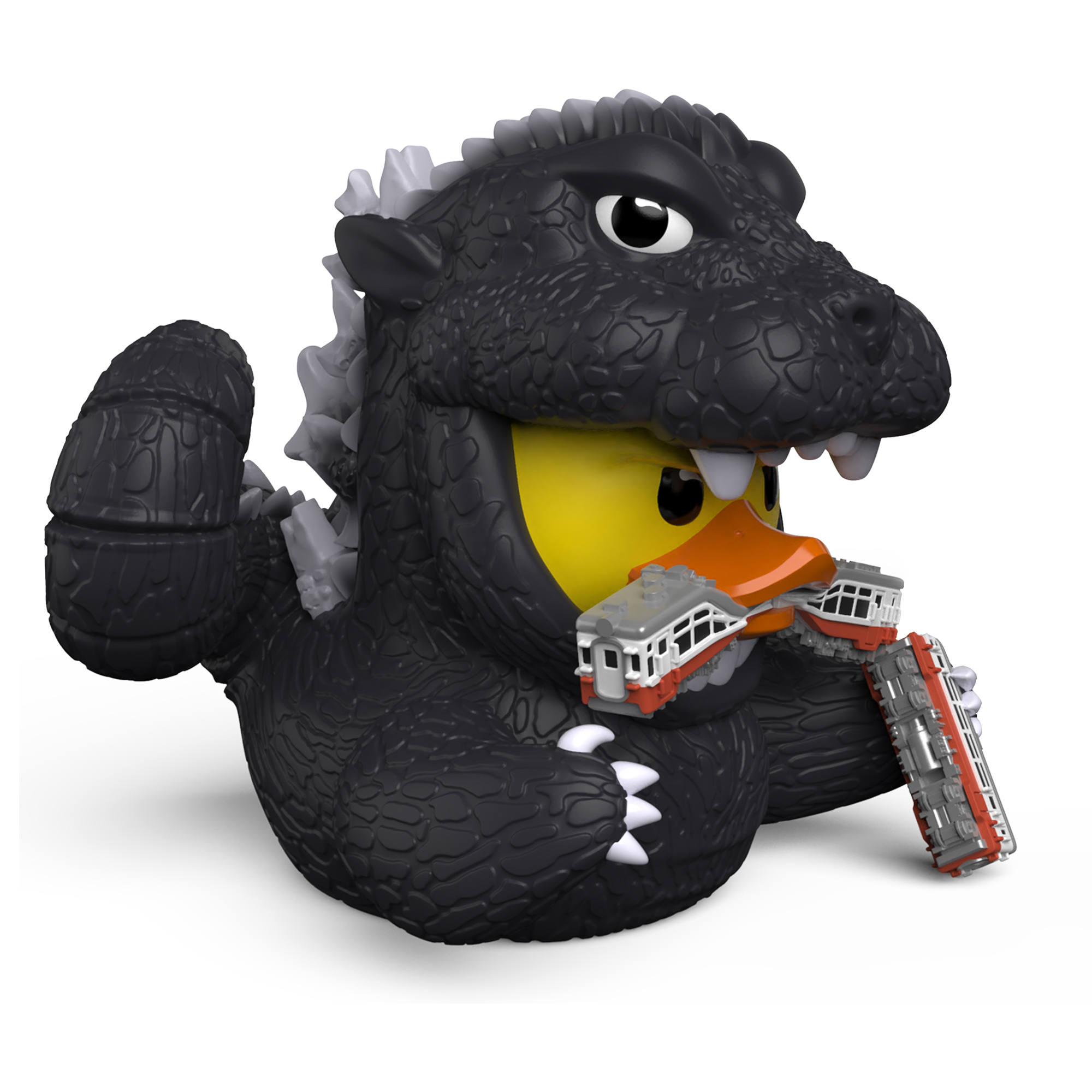 Egy Godzilla gumikacsa vonatokat tart a kezében és szájában.