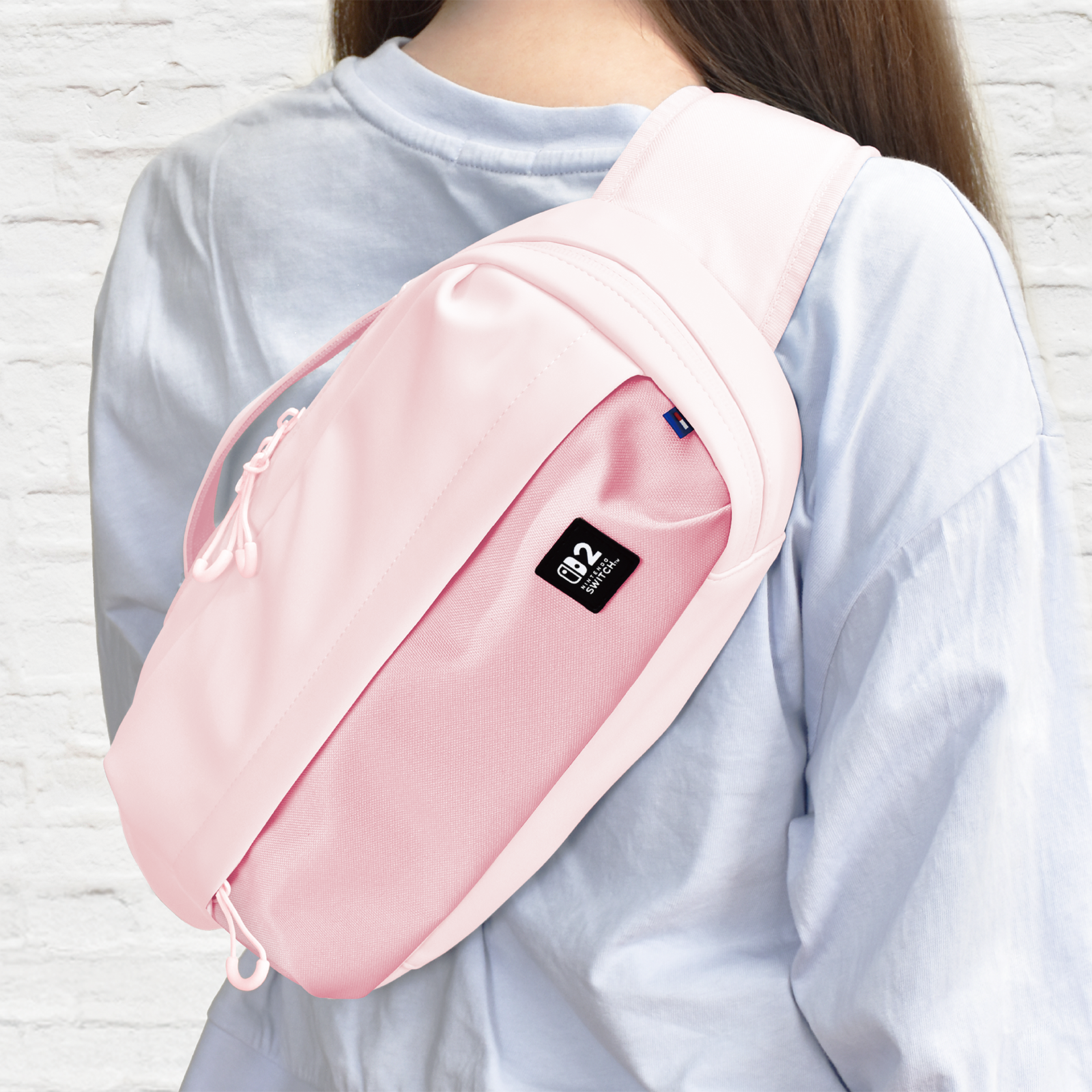 Eine Person trägt einen rosa Gurtbeutel über einem hellblauen Hemd.