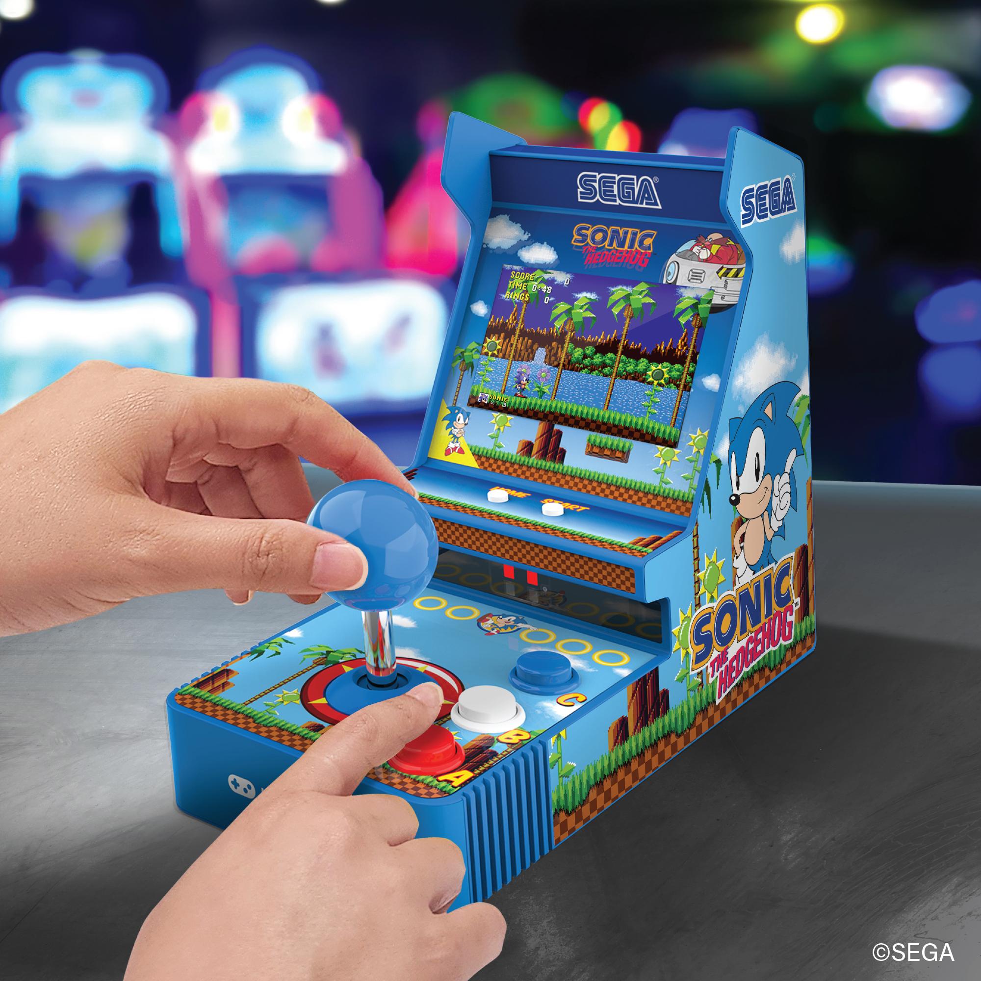 Sonic the Hedgehog'lu mavi mini atari makinesini çalıştıran eller.