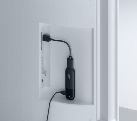 Een zwarte Xiaomi-dongle is via een HDMI-kabel aangesloten op een tv.