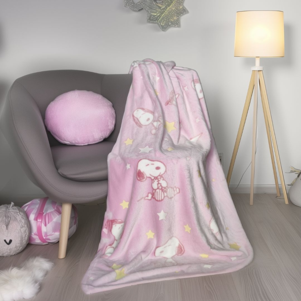 Ein Snoopy-Muster auf einer rosafarbenen Decke auf einem grauen Sessel.