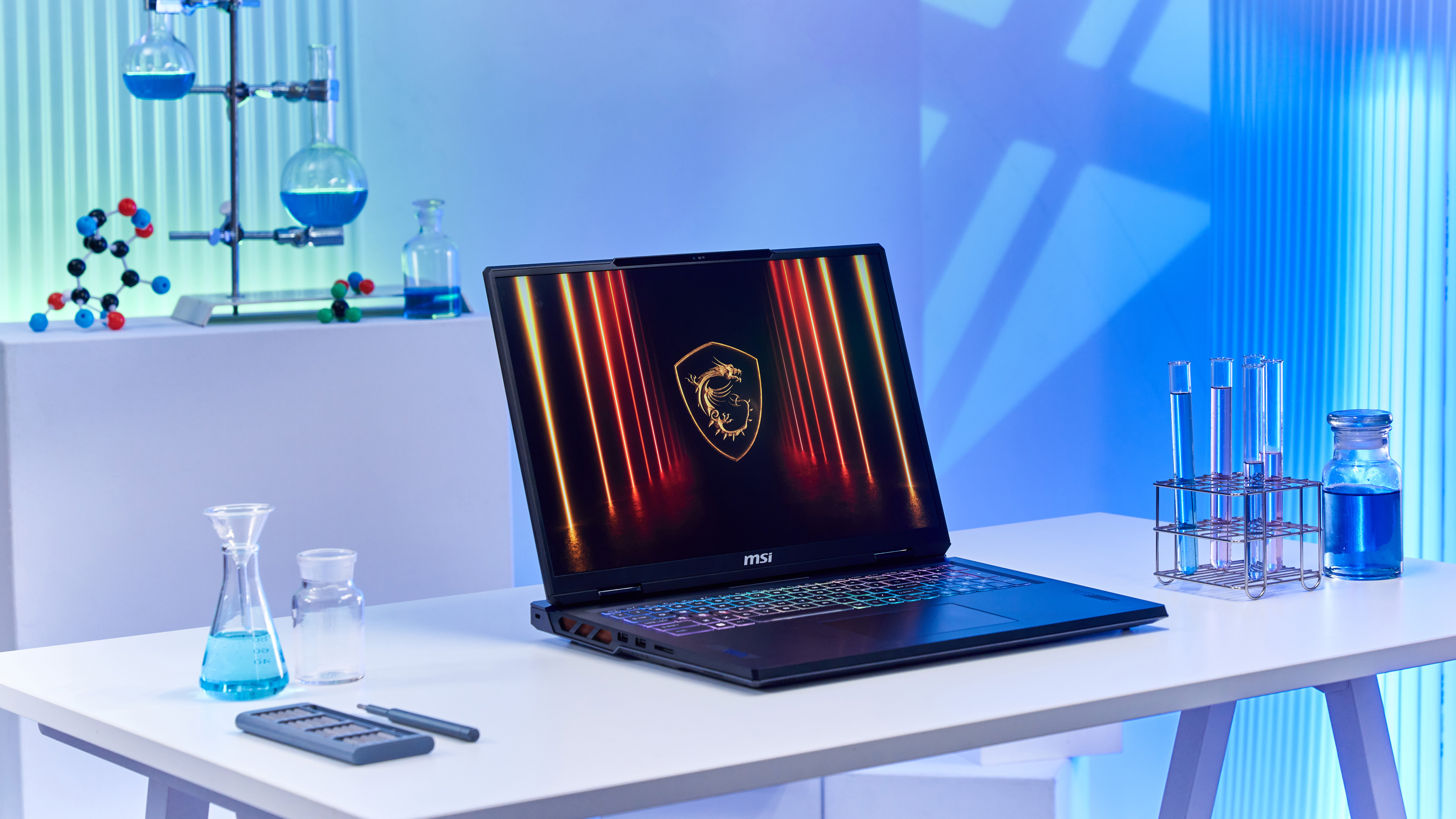 MSI-Laptop auf einem Tisch mit Laborgeräten. Blaue Flüssigkeit in Kolben und Reagenzgläsern.