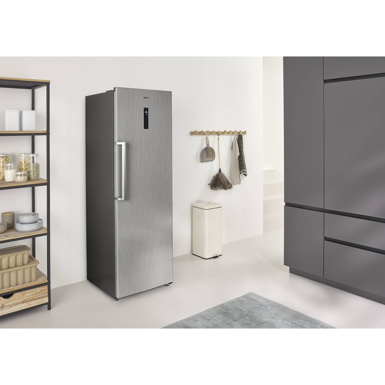 Uno spazio cucina moderno con frigorifero argentato, mensole e cestino.