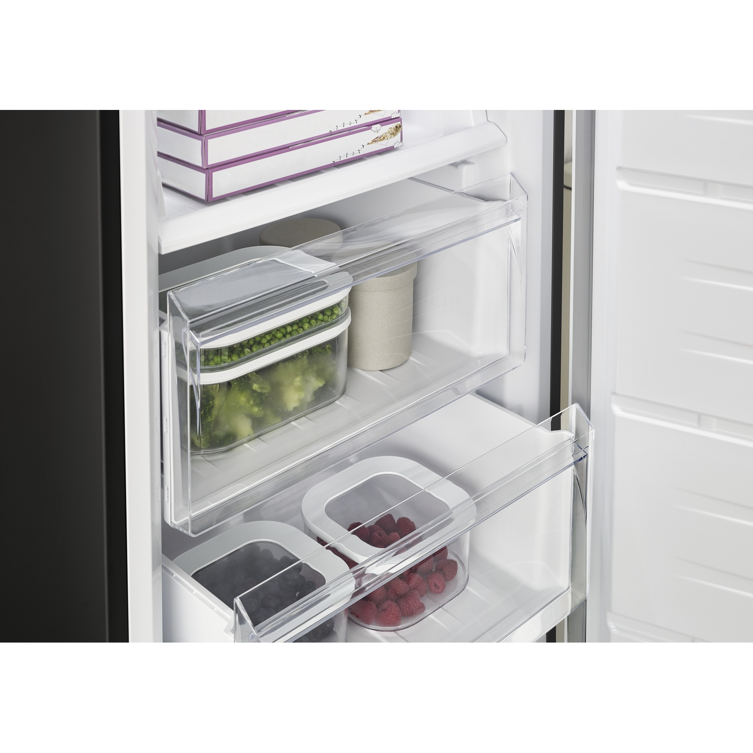 Interno congelatore con cibo: bacche, broccoli e piselli in contenitori.