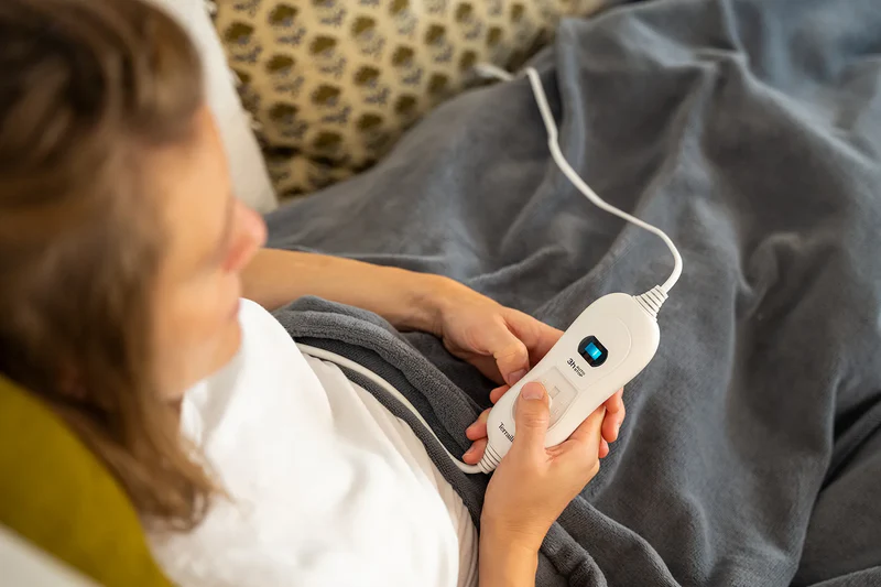 Una donna tiene un controller di coperta elettrica bianco con display blu.
