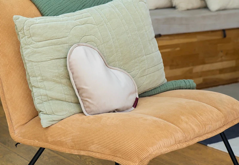 Un fauteuil orange avec plusieurs coussins, dont un coussin en forme de cœur.