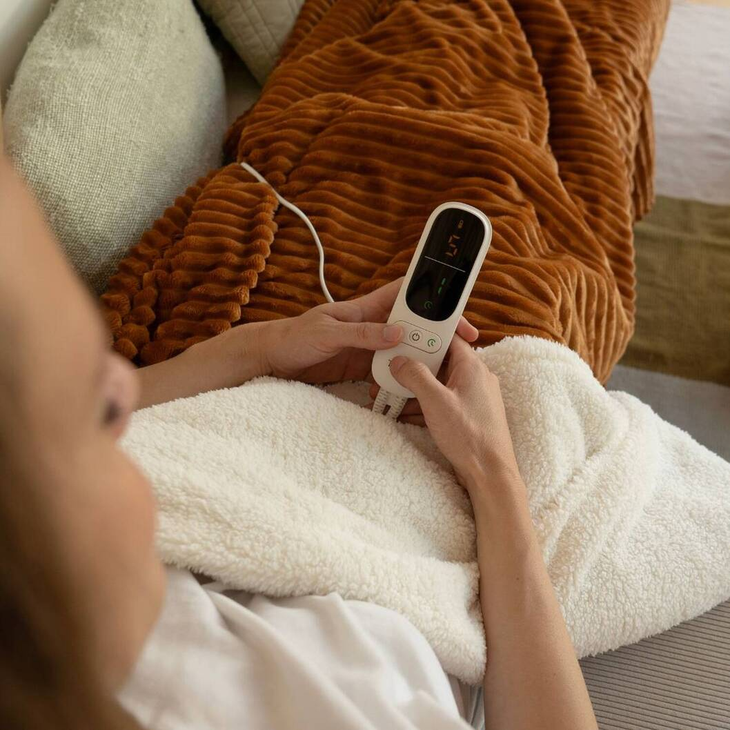 Una persona tiene in mano il telecomando di una coperta riscaldata.