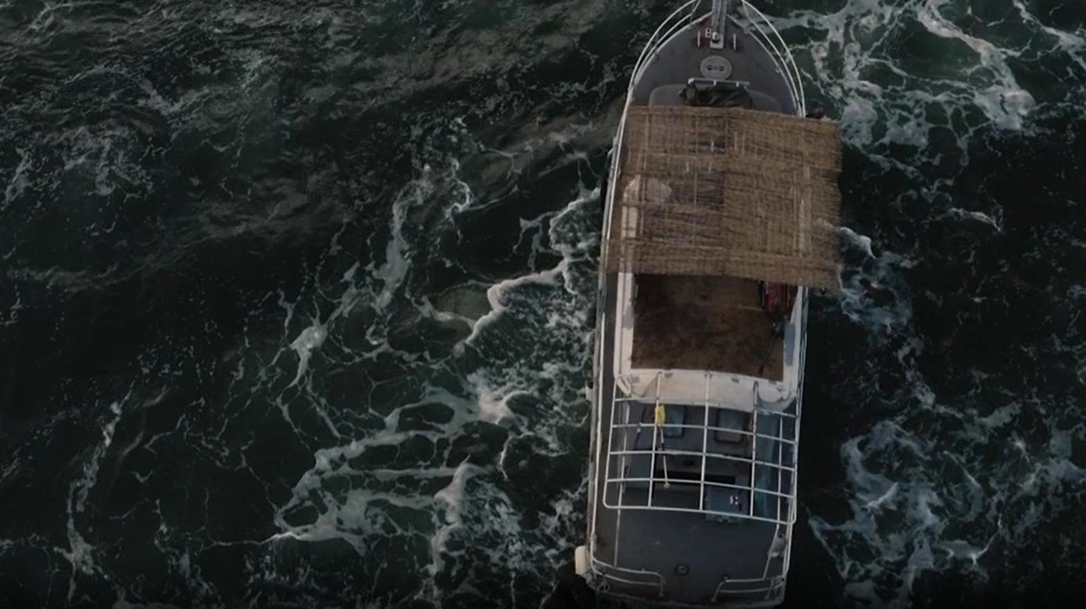 Ein Boot fährt auf dem dunklen Meer, Wellen schlagen.