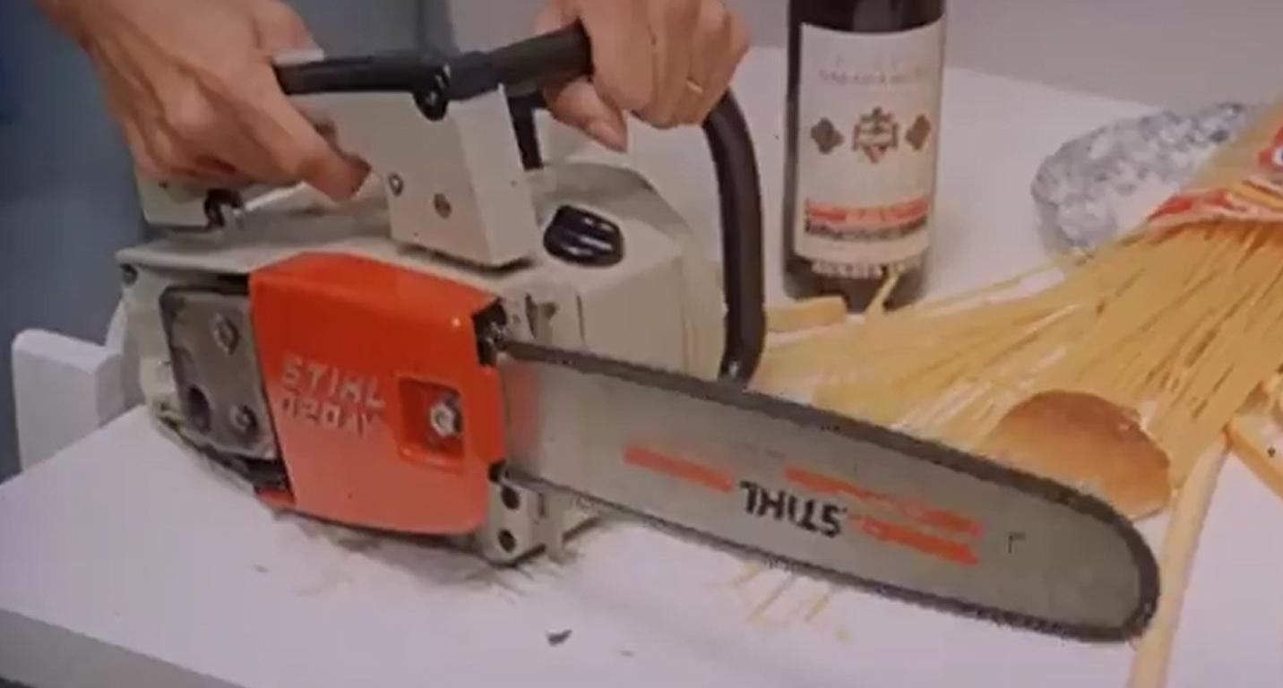 Eine Kettensäge liegt auf einem Tisch neben Nudeln und einer Flasche.