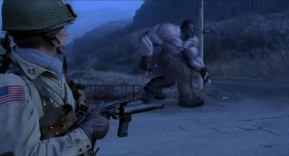Ein Soldat mit Waffe blickt auf ein großes, muskulöses Wesen.