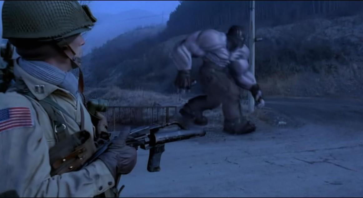Soldat mit Waffe blickt auf riesiges Monster in nebliger Landschaft.